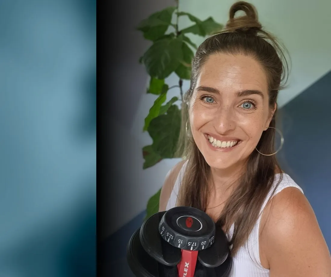 Madeleine smiling with an adjustable dumbbell, mid-workout
