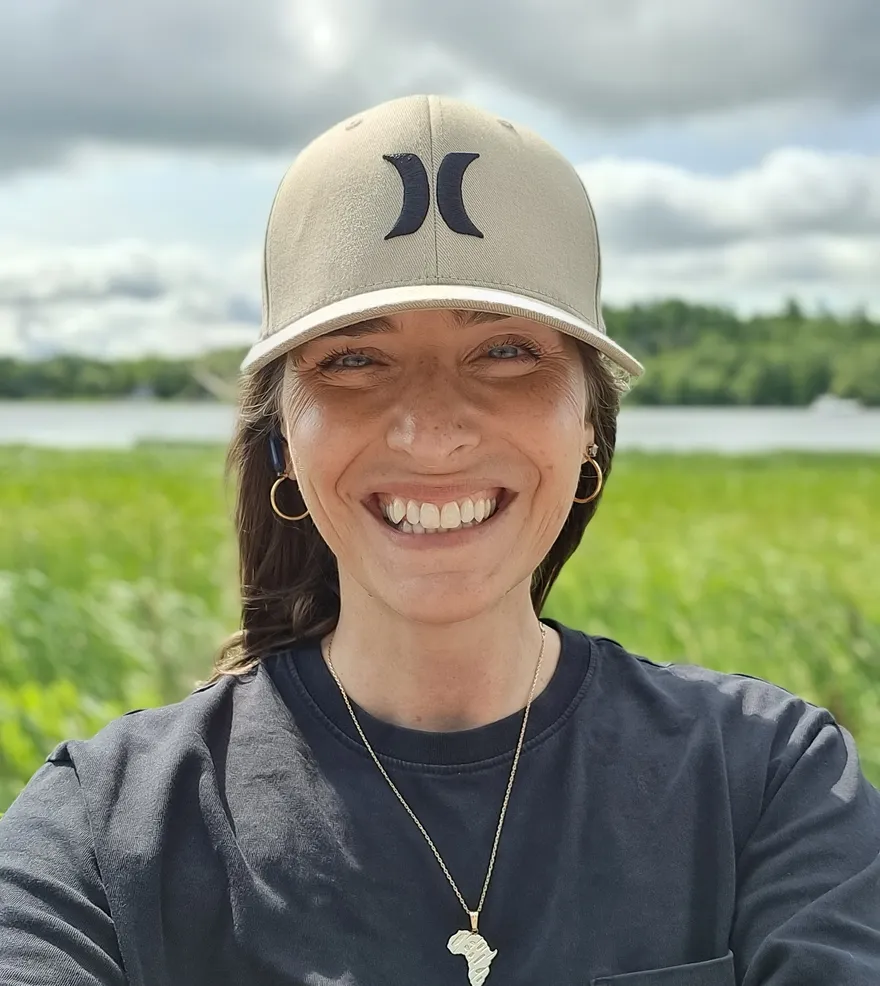Madeleine Nali smiling, wetlands and water behind her